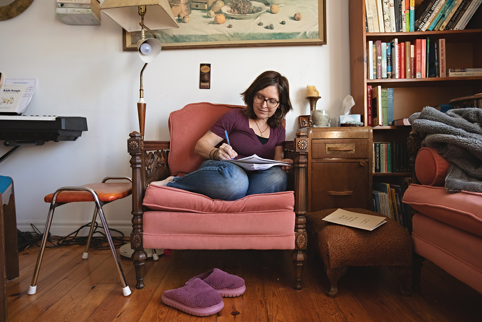 Author Erica Richmond sits on a plush chair in her home library, writing in a journal.